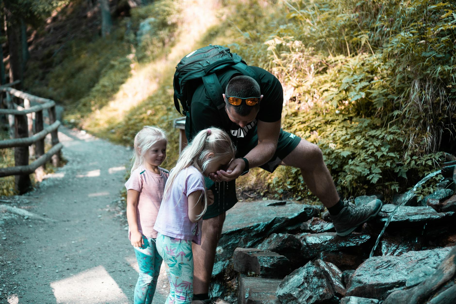 Famille avec enfants en randonnée sur un sentier de montagne avec sacs à dos colorés