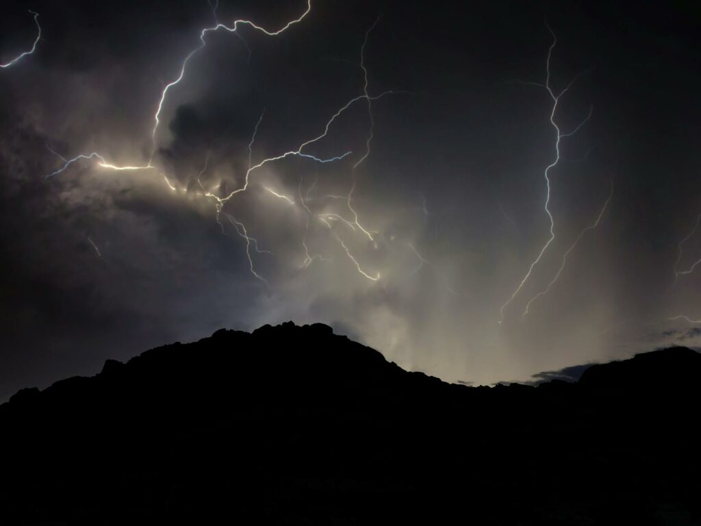 Orage en formation au-dessus de sommets de montagne, paysage menacant avec nuages cumulonimbus et éclairs lointains