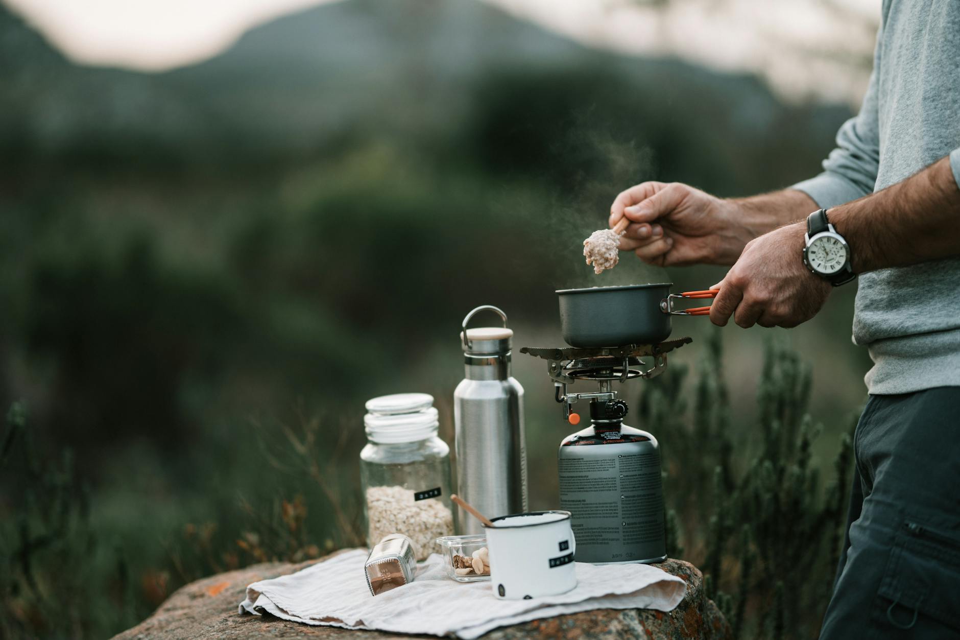 Randonneur préparant un repas en bivouac alpin, couteau pliant à portée de main