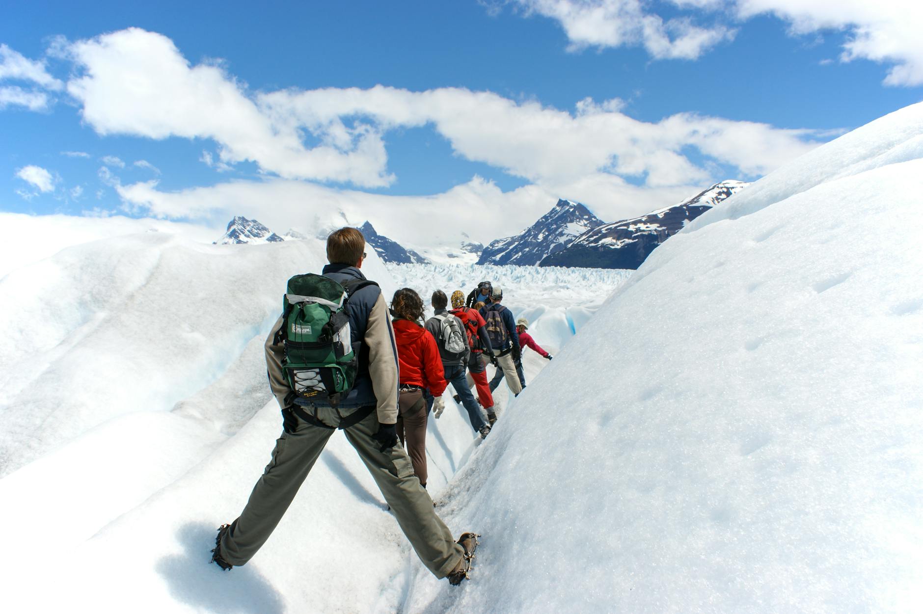 Randonneur équipé de crampons légers progressant sur un sentier enneigé en montagne au printemps
