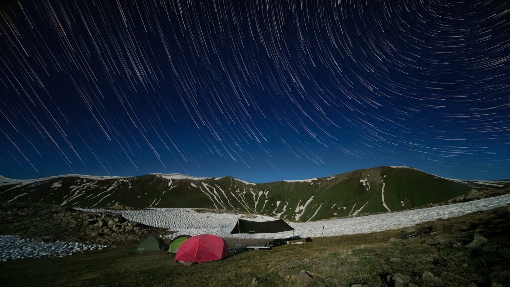 Famille installant son bivouac au coucher du soleil en montagne, tente dressée face au panorama alpin