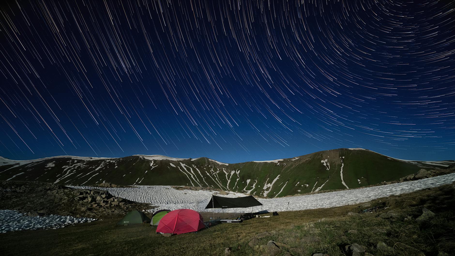 Famille installant son bivouac au coucher du soleil en montagne, tente dressée face au panorama alpin