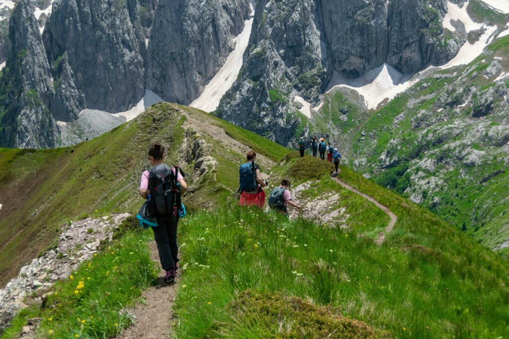 Groupe d'enfants de primaire en randonnée sur un sentier de montagne en 2026, encadrés par leur enseignant