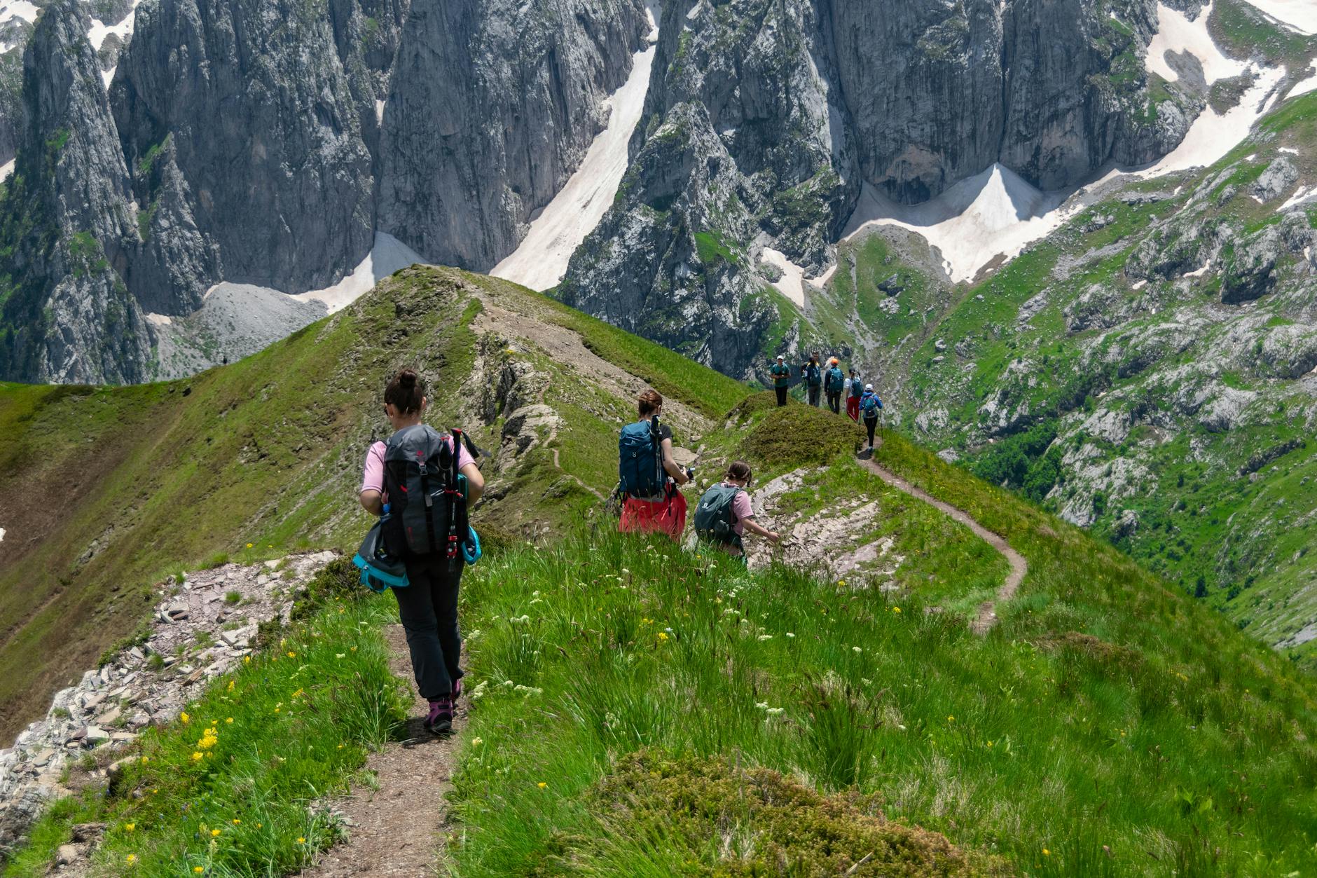 Groupe d'enfants de primaire en randonnée sur un sentier de montagne en 2026, encadrés par leur enseignant