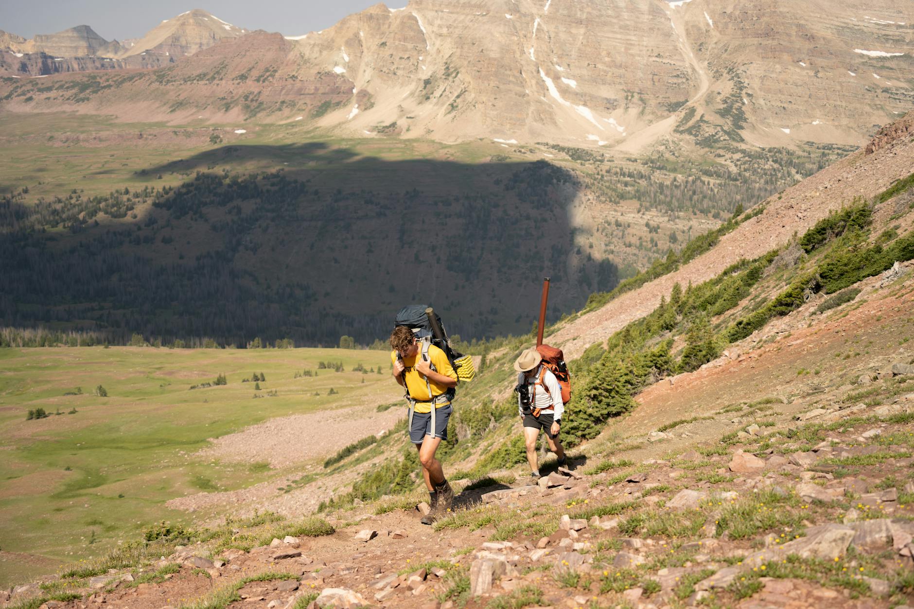 Parent portant son bébé dans un porte-bébé dorsal sur un sentier de randonnée en montagne au printemps 2026