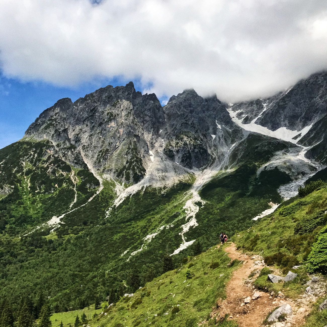 Randonneur progressant sur un sentier de montagne au pied des falaises calcaires du Vercors en été