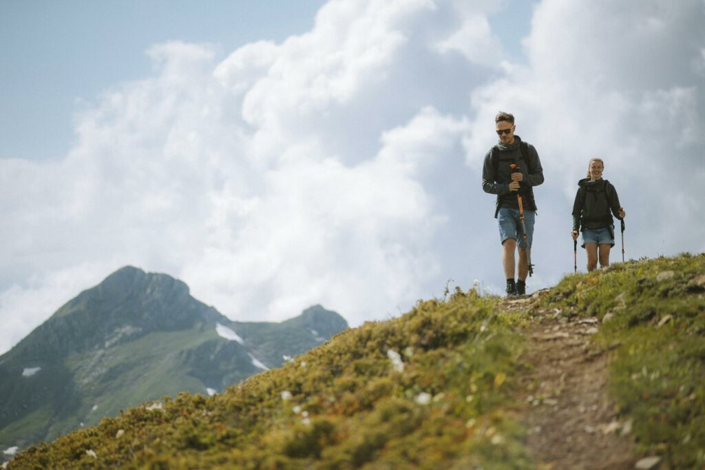 Famille en randonnée sur un sentier de montagne avec un jeune enfant porté dans un porte-bébé dorsal