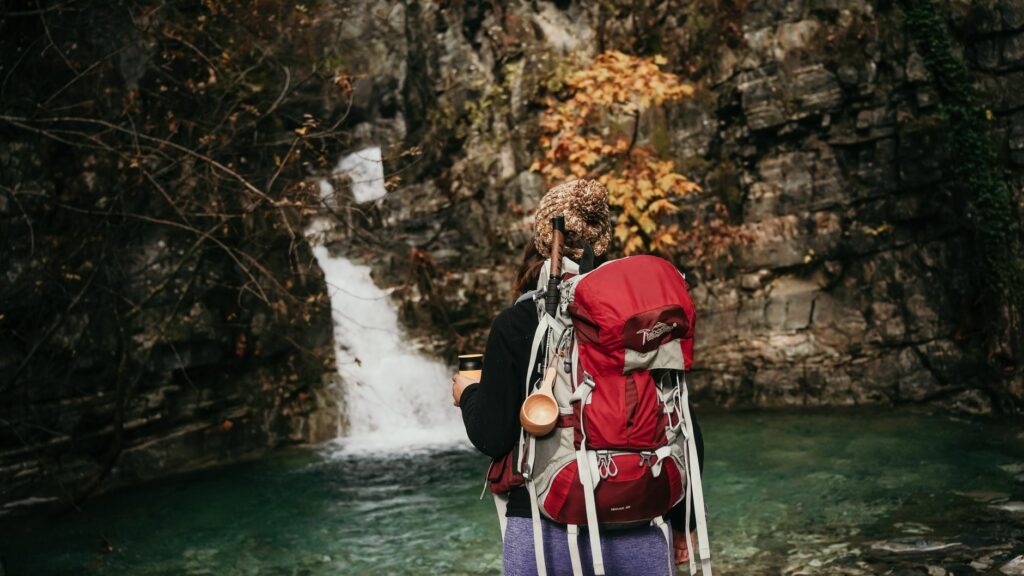 Randonneur remplissant une gourde filtrante directement dans un ruisseau de montagne lors d'une randonnée en 2026