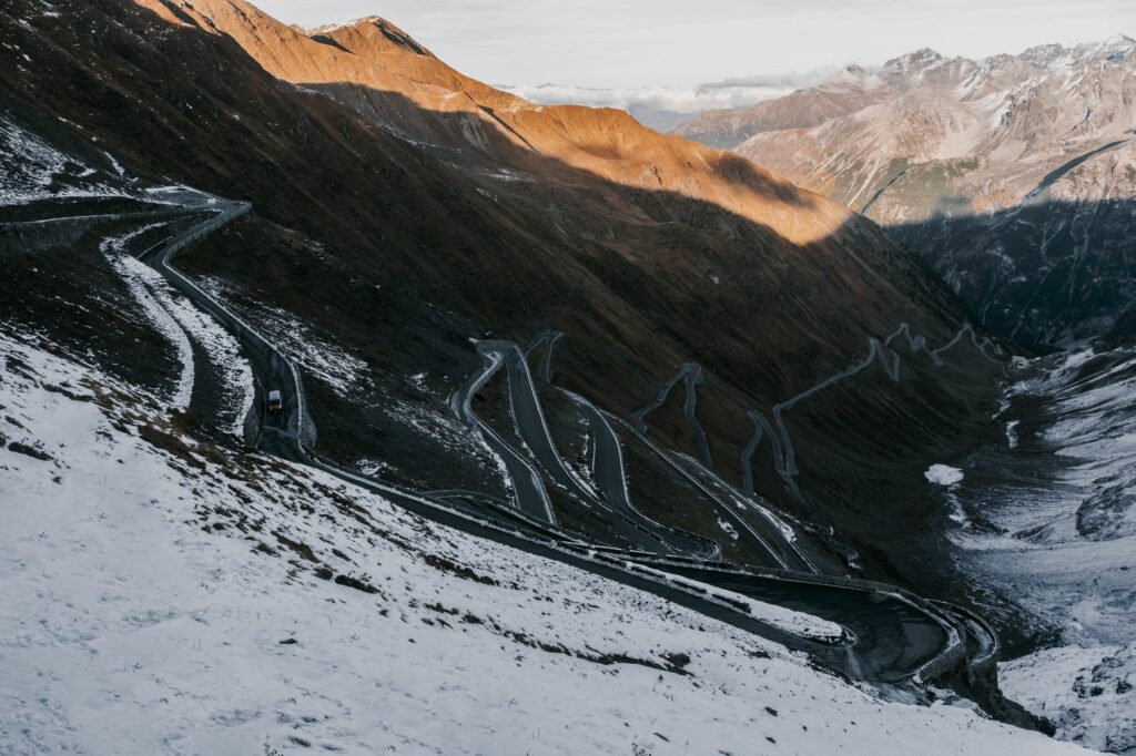 Route de montagne serpentant entre deux murs de neige au sommet d'un col alpin lors de sa réouverture printanière 2026