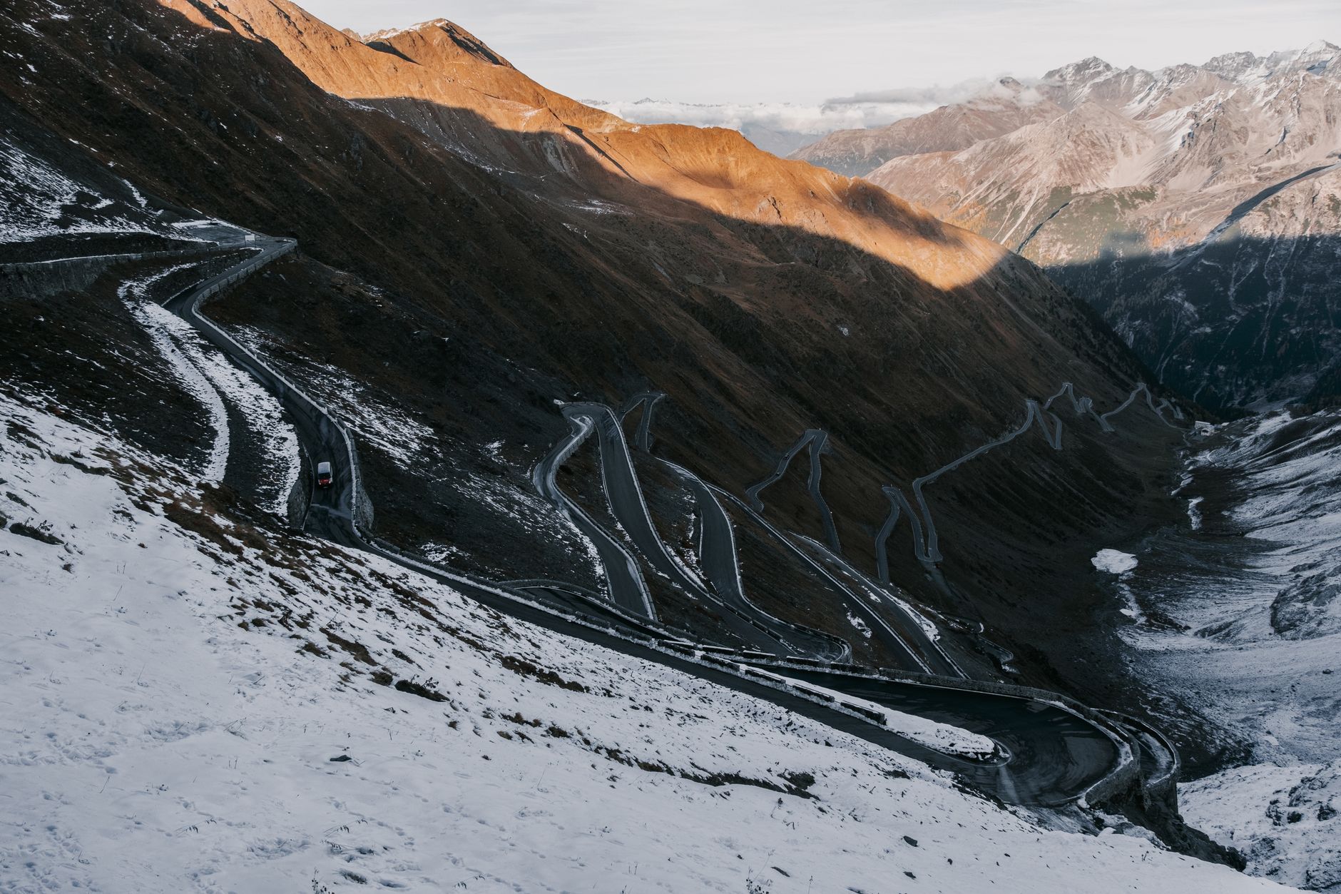 Route de montagne serpentant entre deux murs de neige au sommet d'un col alpin lors de sa réouverture printanière 2026