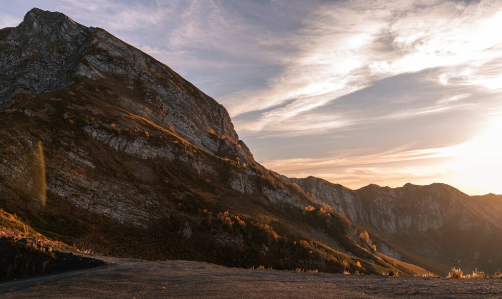 Photographe amateur cadrant un panorama de sommets montagneux au lever du soleil, lumière dorée sur la crête en 2026