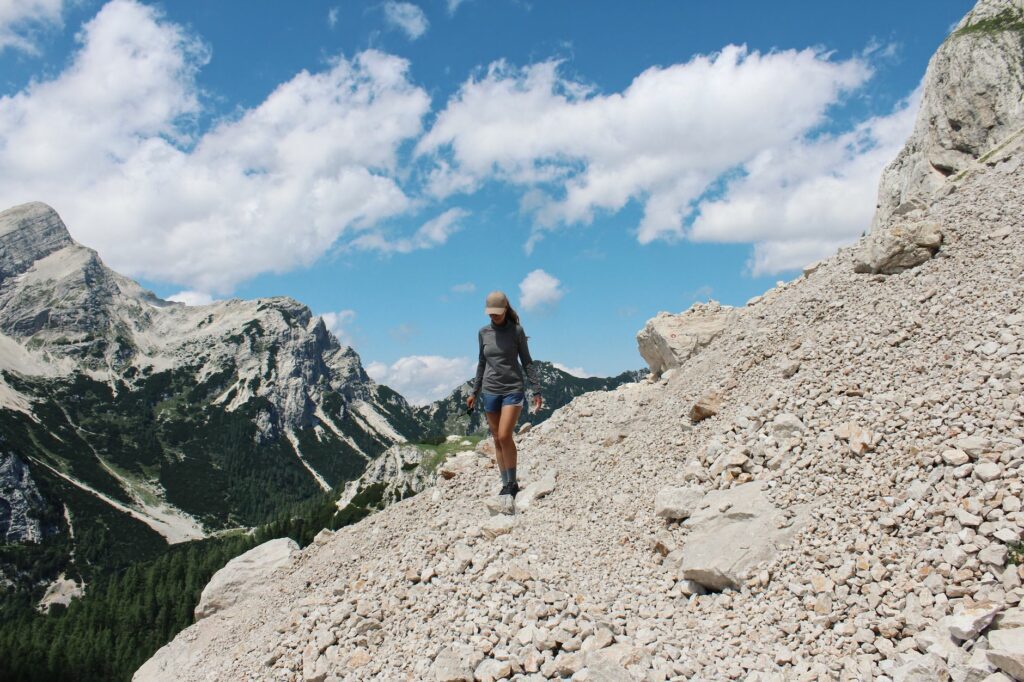Randonneuse marchant seule sur un sentier de montagne au lever du jour, sac à dos chargé pour un trek de plusieurs jours