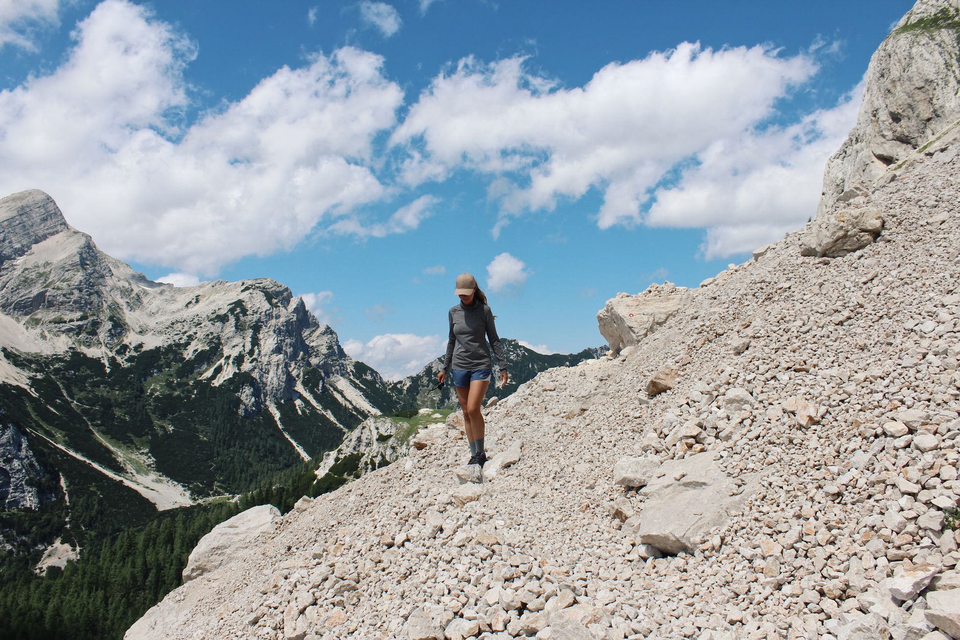 Randonneuse marchant seule sur un sentier de montagne au lever du jour, sac à dos chargé pour un trek de plusieurs jours