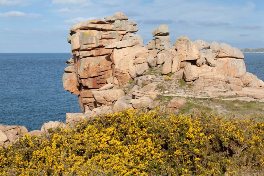 Sentier côtier balisé du GR34 le long des falaises bretonnes du Morbihan, avec phare en arrière-plan sur la côte sauvage