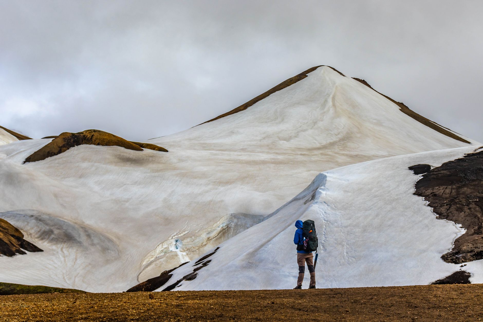 Randonneur équipé pour l'hiver sur un sentier de montagne enneigé, illustration des achats outdoor à prévoir en 2026